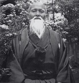 Morihei Ueshiba standing in a garden